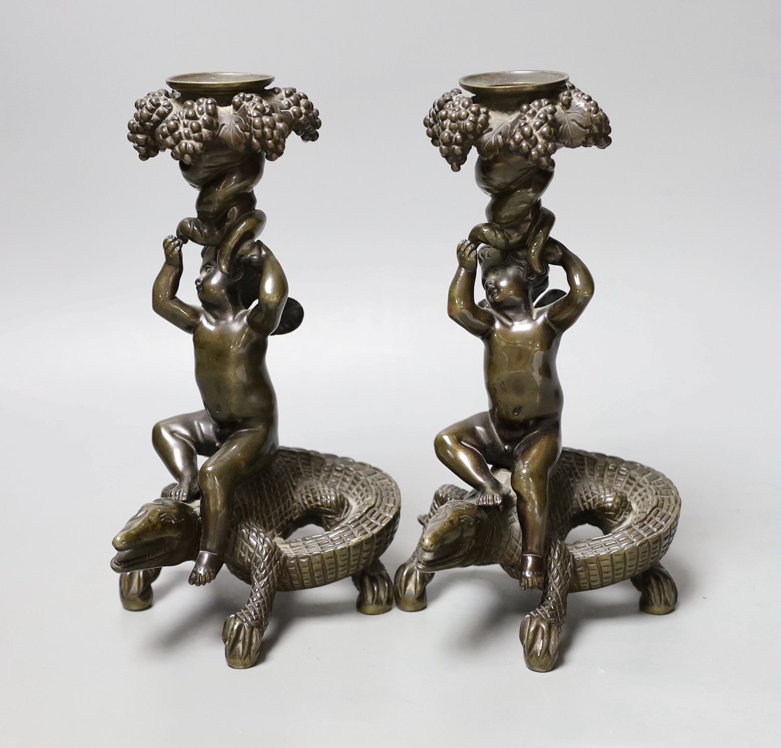 A pair of late 19th century bronze candlesticks modelled as cherubs riding crocodiles, 21.5cm